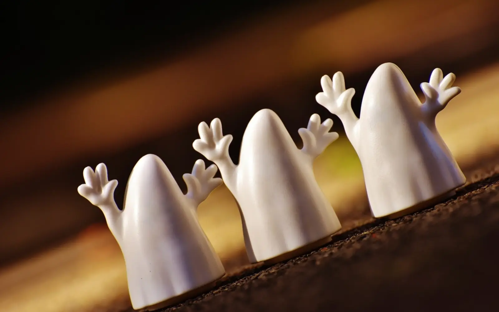 Three little white ghost figures with raised arms