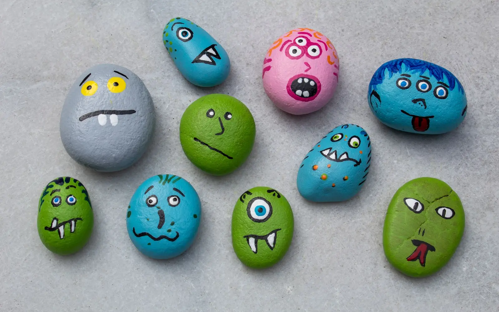 Hand-painted rocks decorated as colorful smiling monsters