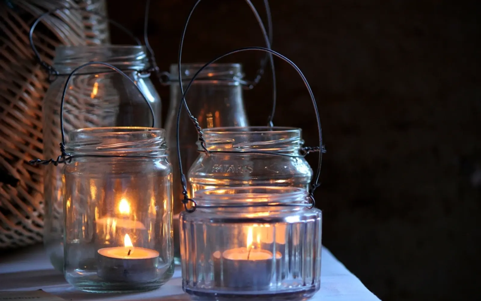 Mason jar lanterns with wire handles glowing with tea lights
